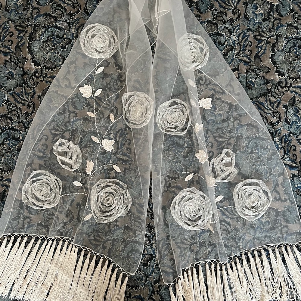Sheer white shawl with tassels at hem and sequins and ribbon work.